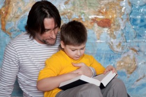 Dad and son reading a book on a map of the world